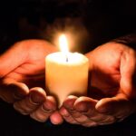 A person holding a candle Description automatically generated